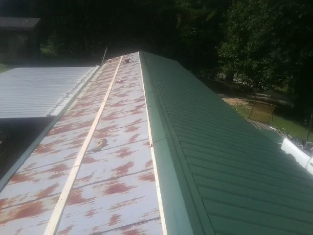 Old rusted panels beside newly installed green metal roofing — Wind Damage Roof Repair by Roofing Brothers in Hatfield