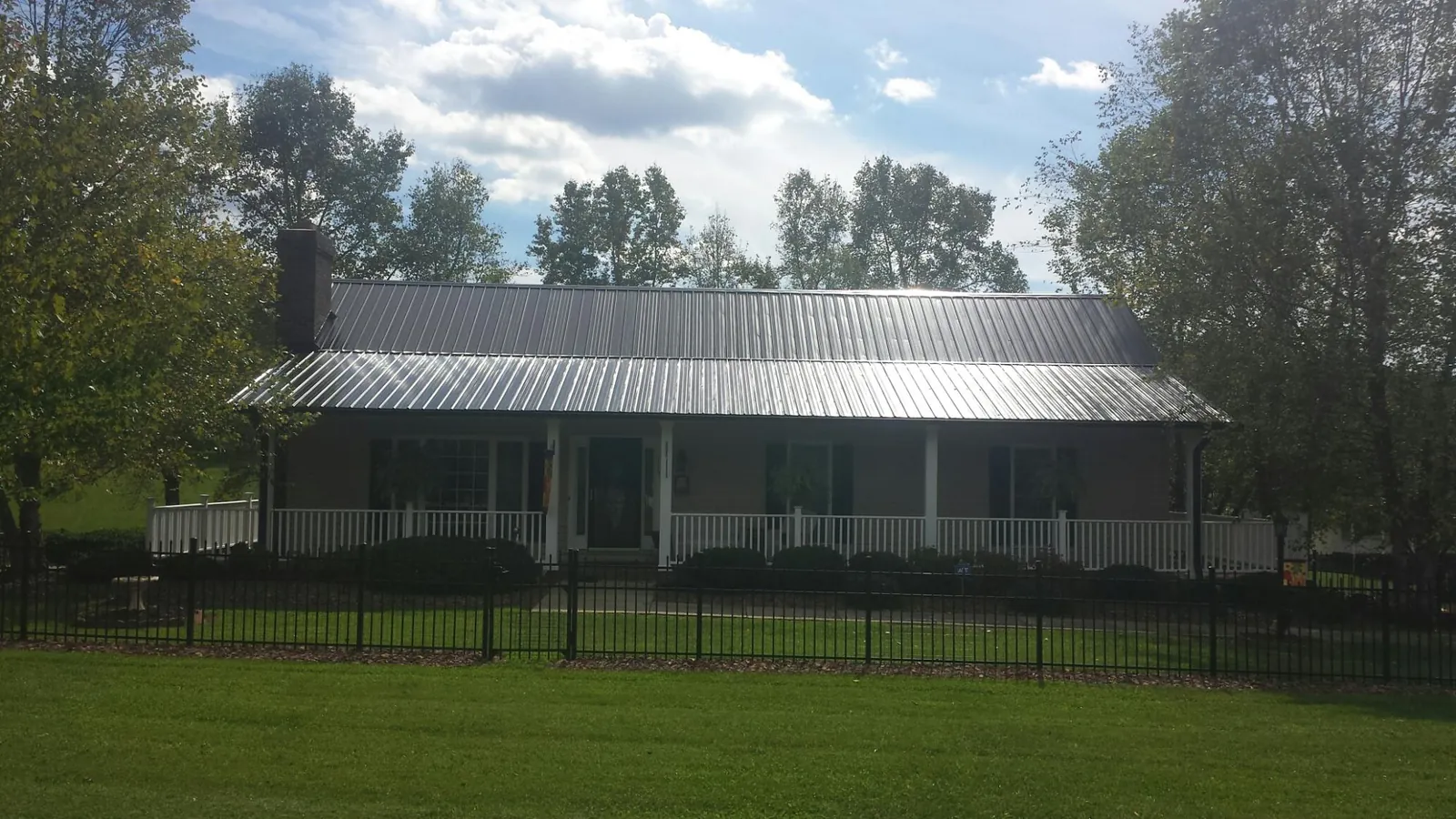 Gray metal roof on a brick ranch with a full width front porch — Gutter Guard Installation work by our crew in Hatfield