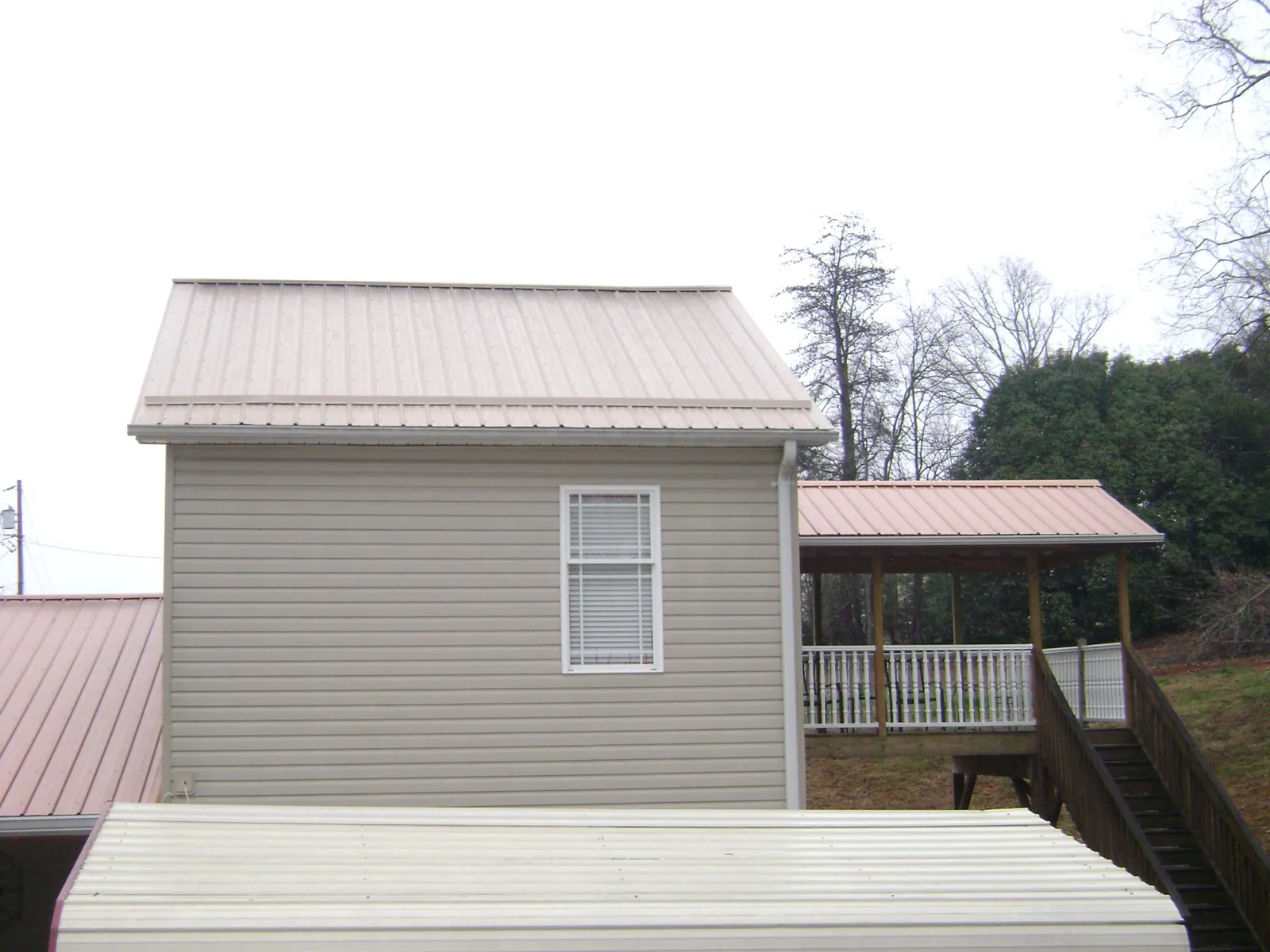 Tan metal roofs on a two story addition and attached porch, from a Roof Replacement job in Hatfield